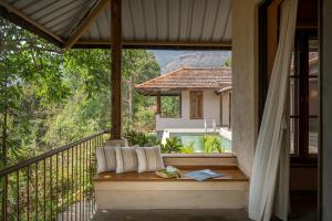 a balcony with a bench and a view of a house at SaffronStays Rustic Trails in Mulshi