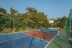 a tennis court with a net on top of it at SaffronStays Rustic Trails in Mulshi