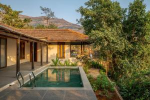 a house with a swimming pool in front of a house at SaffronStays Rustic Trails in Mulshi