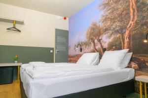 a large bed in a room with a painting on the wall at Giethoorn Old Art Hotel in Giethoorn