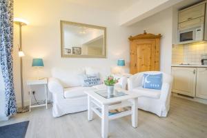 a living room with two white chairs and a table at Am Austernstrand in List +2 photos
