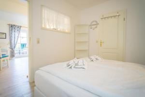 a bedroom with a white bed with two towels on it at Am Austernstrand in List