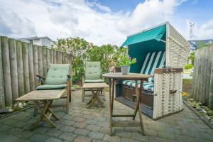 a patio with two chairs and a table and a fence at Am Austernstrand in List