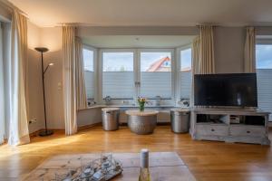 a living room with a flat screen tv and large windows at Lister Reede Garten in List