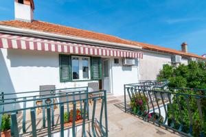 a white house with green shutters and a balcony at Nikola apartment in Božava