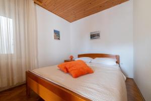 a bedroom with a bed with an orange pillow on it at Nikola apartment in Božava