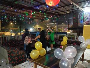 a group of people standing around a table with balloons at The BVM Hostel in Mumbai