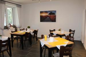 a dining room with tables and chairs and a painting on the wall at Hotel Brunnenhof in Roetgen