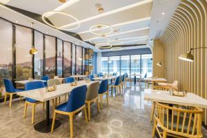 a restaurant with tables and chairs and windows at Atour Hotel Maqun Nanjing in Nanjing