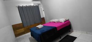 a small room with a bed with pink and blue at Pousada familiar 05 in Rio do Sul