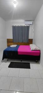 a bedroom with a bed with a pink and blue blanket at Pousada familiar 05 in Rio do Sul