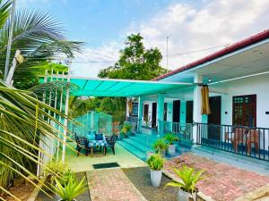 a house with a blue roof with a patio at NMK Trinco Holiday Inn in Trincomalee