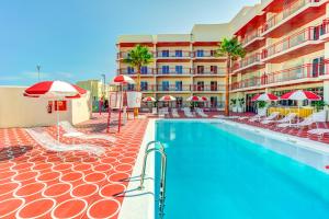 a swimming pool with chairs and umbrellas next to a hotel at Romeos Ibiza - Adults Only in San Antonio Bay