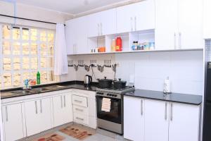 a kitchen with white cabinets and a stove top oven at Zaya Luxe Home in Naivasha