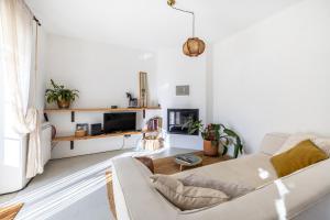 a white living room with a couch and a tv at Casinha Revira Volta in Nesperal