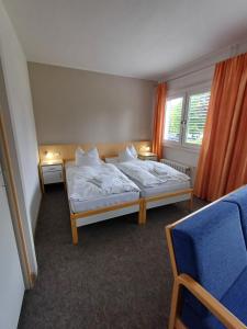 a bedroom with two beds and a blue chair at Hotel am Lärchenberg in Schirgiswalde +12 photos