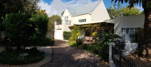 a white house with a fence in front of it at Jonquil Guest Cottage in Franschhoek