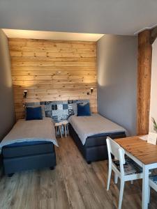 a bedroom with two beds and a wooden wall at Bed And Breakfast Geertruidahoeve in Hellendoorn