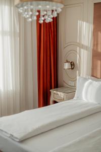 a bedroom with a white bed and a red curtain at Grădina Mariajelor Hotel in Câmpulung Moldovenesc +72 photos