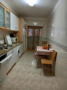 a kitchen with a table and a sink and a stove at Vilamoura Seaside Serenity T3 AP - Pool, BBQ, 3min Walk to Beach in Quarteira