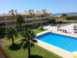 an apartment with a swimming pool in front of a building at Vilamoura Seaside Serenity T3 AP - Pool, BBQ, 3min Walk to Beach in Quarteira