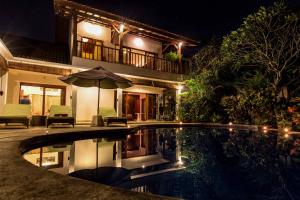 a house with an umbrella and a swimming pool at night at Villa Bali Zen Kerobokan in Kerobokan
