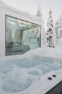 a hot tub covered in snow with snow covered trees at Northern Lights Ranch in Levi