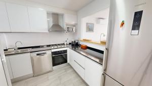 a white kitchen with white cabinets and a refrigerator at Apto Mar Blau in L'Ampolla