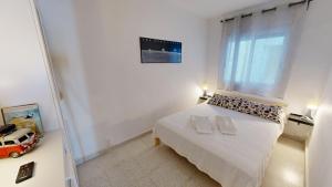 a white bedroom with a bed and a window at Apto Mar Blau in L'Ampolla