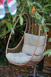 a wicker chair with white pillows sitting in a tree at Au Gré Des Lis - La Suite Du Chêne in Belval-sous-Châtillon
