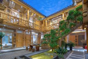 a large wooden building with a staircase and plants at Sunlit Snow Mountain Z Naxi Ethnic Style Courtyard in Lijiang