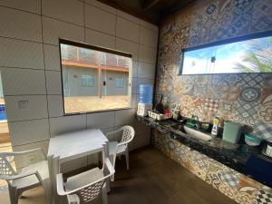 a bathroom with a sink and a table and chairs at Suítes Taipu de Fora in Marau