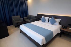 a hotel room with a bed and a chair at Hema's Hotel Supreme in Visakhapatnam
