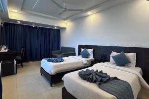 a hotel room with two beds and a desk at Hema's Hotel Supreme in Visakhapatnam