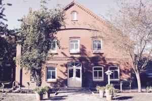 an old brick building with a white door at Hof Steinhütten in Westerhever