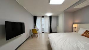 a bedroom with a bed and a flat screen tv at Hoya stay in Yeosu