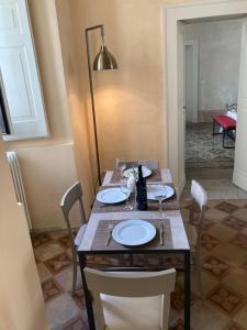 a wooden table with plates and wine glasses on it at Palazzo Cariddi Apartment in Nardò