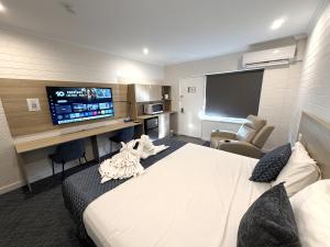 a hotel room with a bed and a flat screen tv at Katherine Motel in Katherine