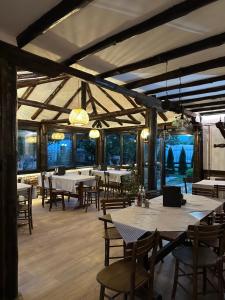 a dining room with tables and chairs and windows at Konak Tosa in Poganovo