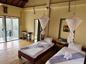 a bedroom with two beds and a balcony at Zen Namkhan Boutique Resort in Ban Xianglôm