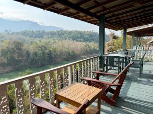 a porch with two chairs and a wooden table on top of a river at Zen Namkhan Boutique Resort in Ban Xianglôm