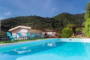 a swimming pool with blue chairs and a house at Villa Terrazza sul Mare in Budoni