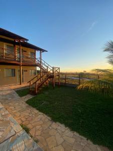 a house with a wooden staircase next to a yard at Suítes Taipu de Fora in Marau