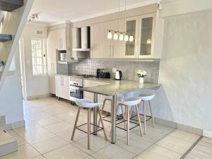 a kitchen with white cabinets and a island with stools at 8 Settler Sands Ocean View in Port Alfred +22 photos
