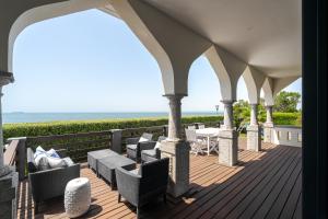 a porch with chairs and tables and the ocean at Blissful Seafront in Cascais