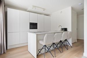 a kitchen with white cabinets and white stools at Eindhoven City Suites Hoogstraat B 4P in Eindhoven +13 photos