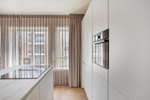 a kitchen with white cabinets and a window at Eindhoven City Suites Hoogstraat B 4P in Eindhoven