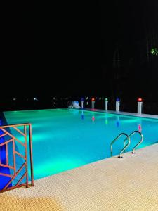 a swimming pool at night with green illumination at Shada Pathor Hotel & Resort in Bholāganj