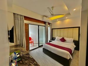 a bedroom with a large bed and a red chair at Shada Pathor Hotel & Resort in Bholāganj +33 photos