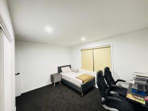 a bedroom with a bed and a couch and chairs at TheQuietPadRest Easy Fly Easy in Christchurch